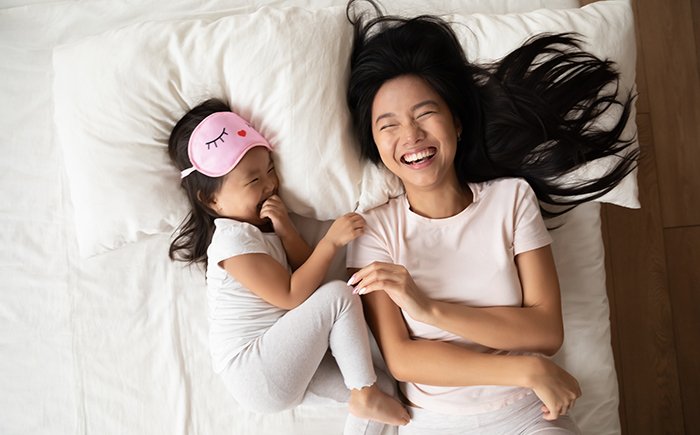 Mom and daughter laughing in bed