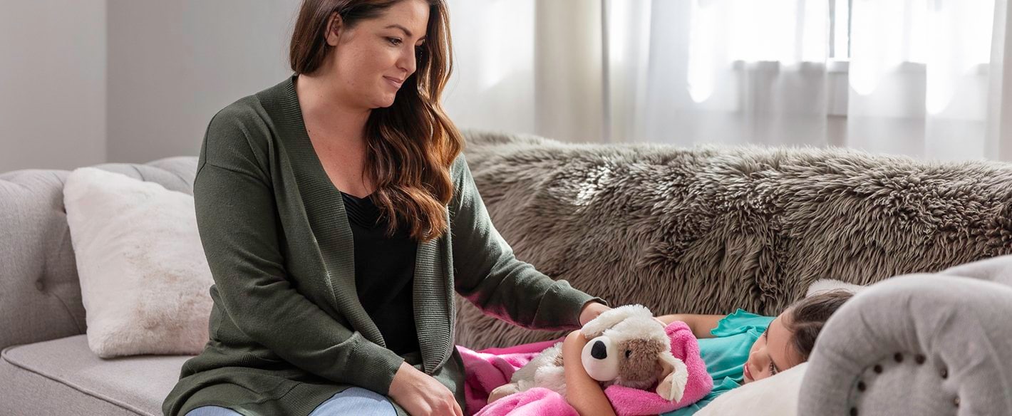 Mother and sick daughter at home on couch