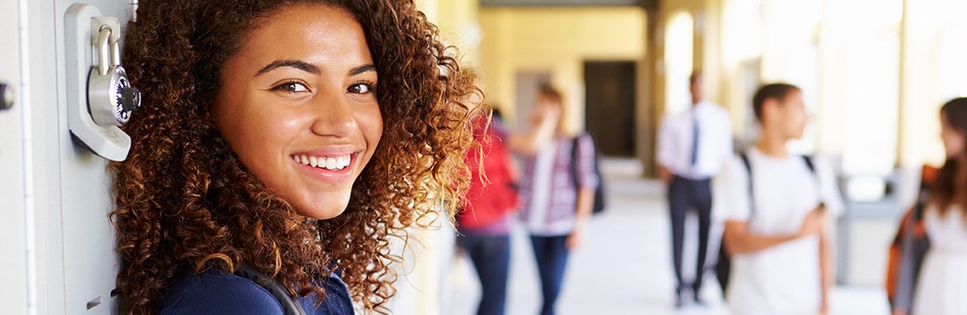 Teen leaning against lockers and smiling